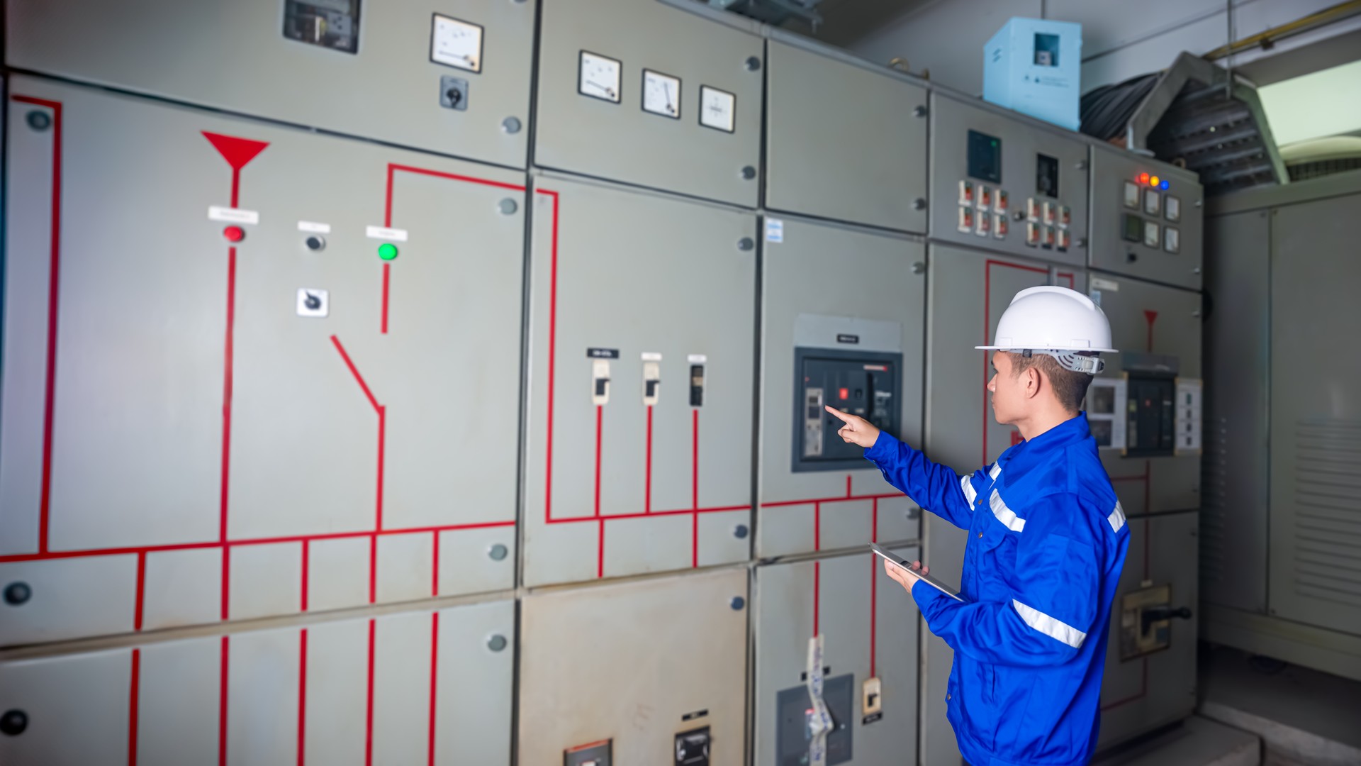 Electrical engineers check the operation of the main electrical control panels and switches, record values on tablets, electrician inspect the electrical systems in the factory.